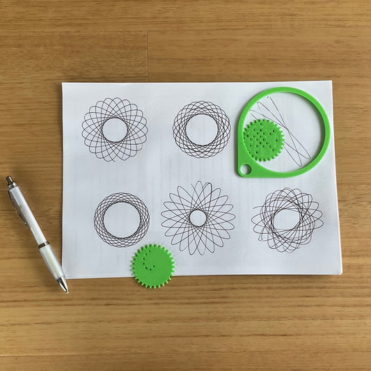A picture of the spirograph on paper with spirograph drawings.