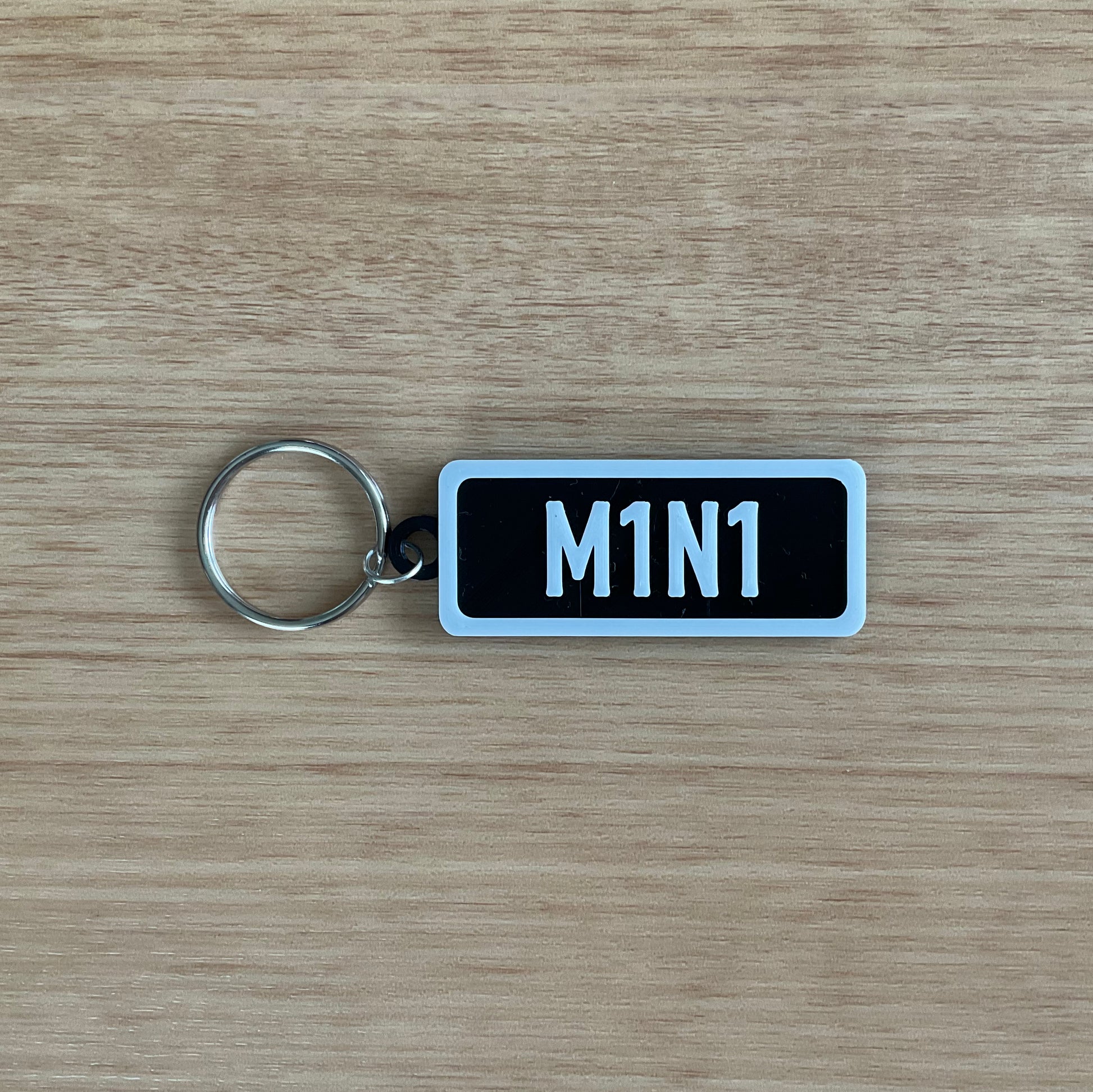 A picture of the Mini keychain in black with white lettering and boarder.