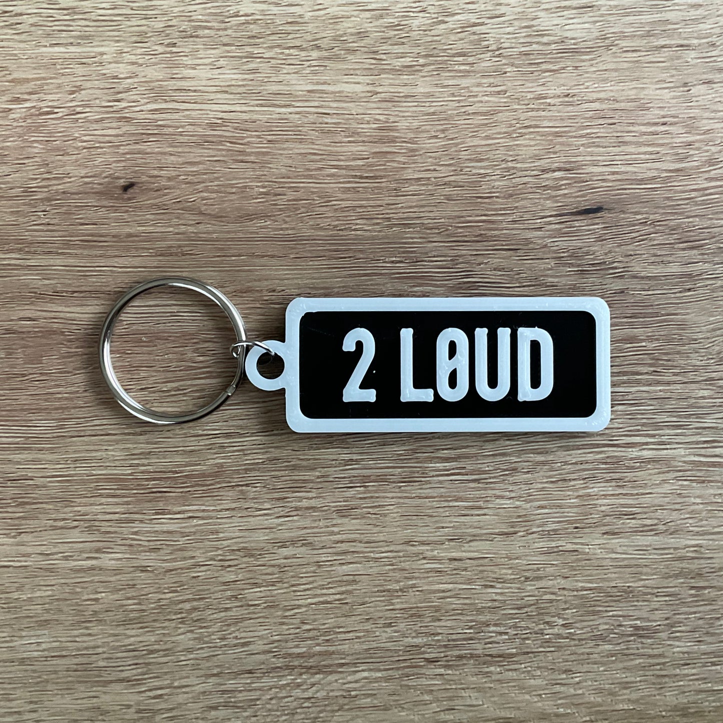 an picture of the white on black version of the too loud numberplate keychain.