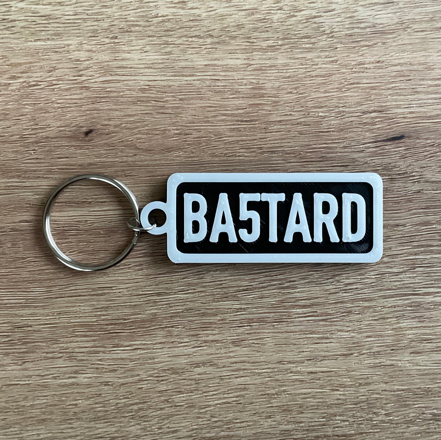 An Image of the White on Black version of the Bastard Keychain.