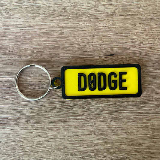 An image of the yellow Dodge numberplate keychain with black border and lettering.