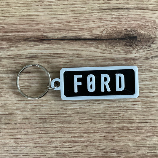 An Image of the Ford Keychain with the black background and white lettering and border. 