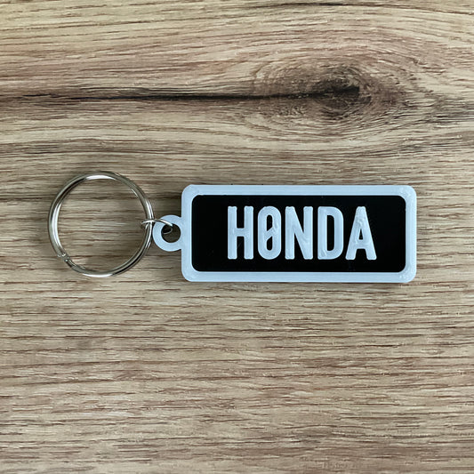 An image of the black Honda keychain with the white lettering and border. 