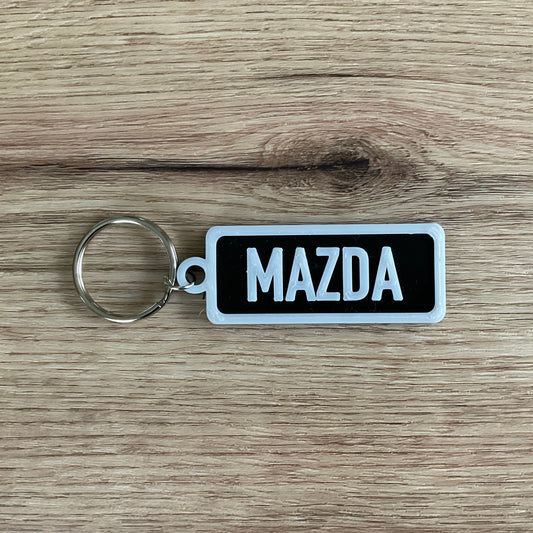An image of the Mazda Keychain in the colour black with white lettering and border