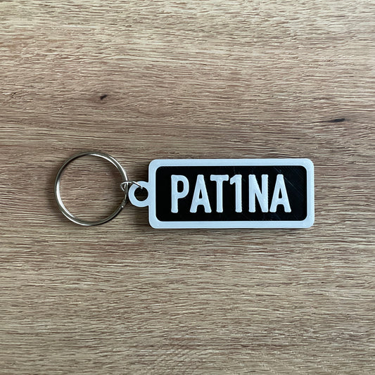 an image of the white on black version of the Patina Numberplate keychain.