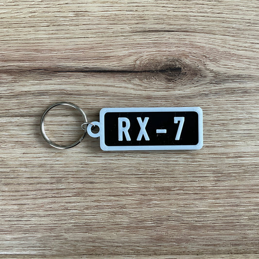 an image of the black r x 7 keychain with white lettering and border