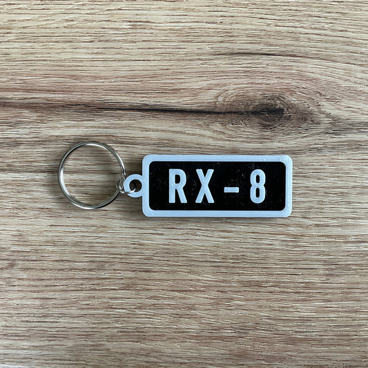 an image of the black r x 8 keychain with white lettering and border.