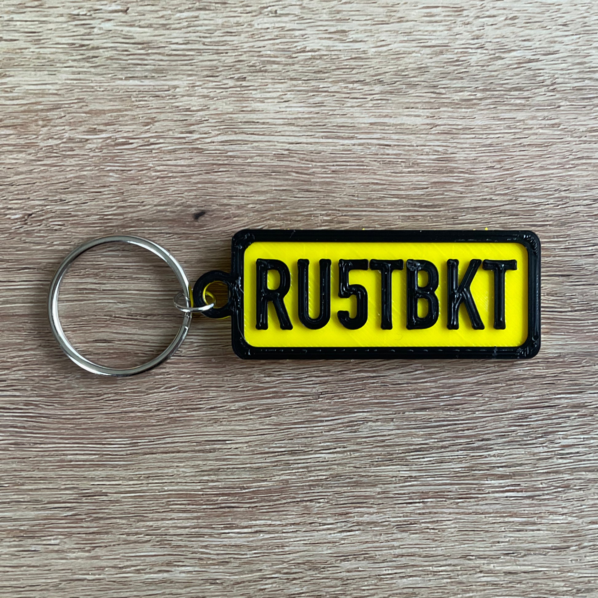 a picture of the rust bucket numberplate keychain in black and yellow.