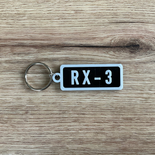 An Image of the black RX-3 Keychain with white lettering and border.