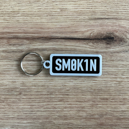 An image of the black smokin keychain with white lettering and border.